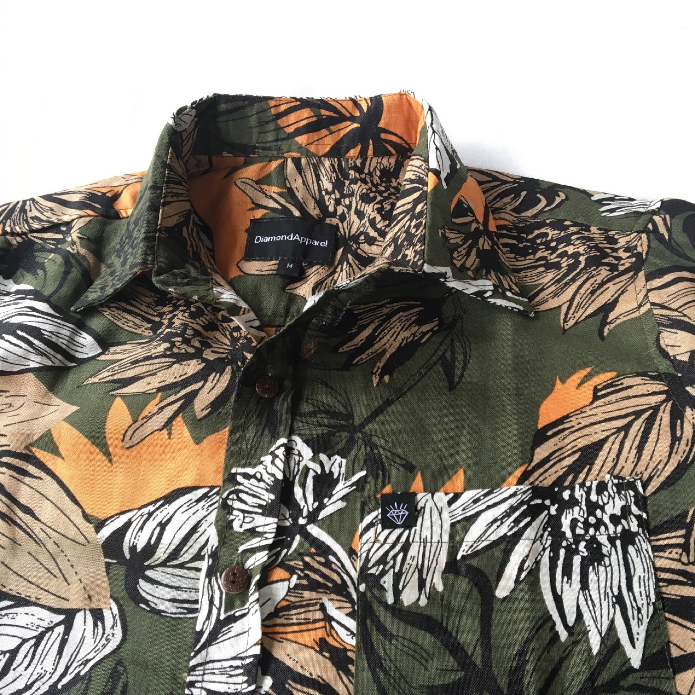 Button-up shirt with an all-over tropical leaf pattern in green, orange and white.